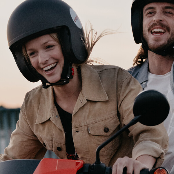 emmy Keyvisual zwei eine junge Frau und ein junger Mann fahren ausgelassen auf einem emmy Roller